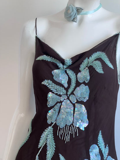 Mannequin wearing a black dress with blue floral embroidery on a plain background