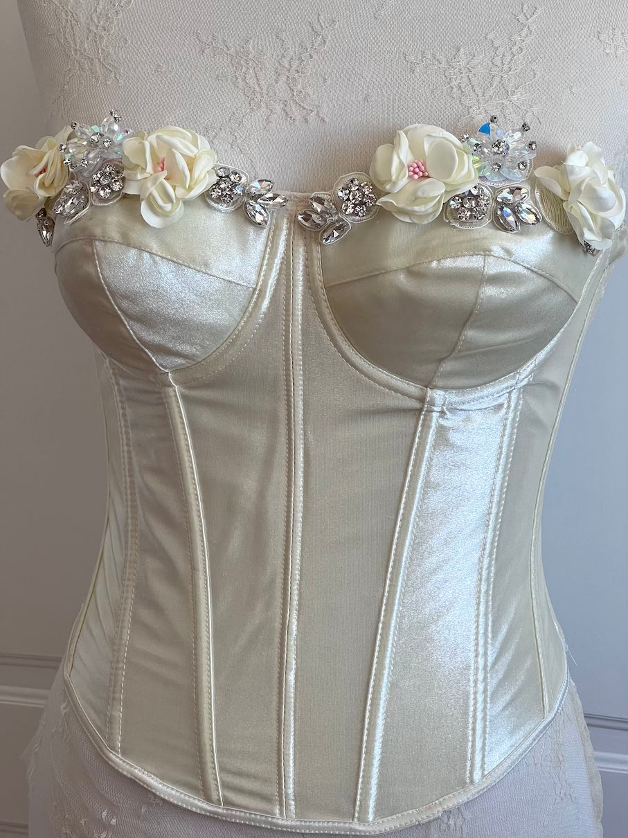 White corset with floral and crystal embellishments on a neutral background