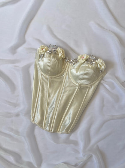 Cream-colored corset with floral and bead embellishments on a white fabric background